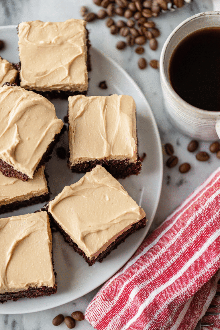 An overhead view of decadent coffee brownies with creamy coffee frosting, arranged neatly on a white plate beside a steaming cup of coffee.